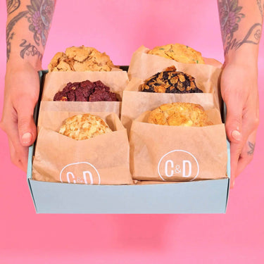 Pick Your Own Cookies box with six assorted chunky New York Cookies from Crumbs & Doilies held against pink background